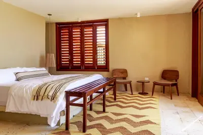 a bedroom with a bed and two chairs and a window at Exclusive 4BR Beach House in Tierra Bomba in Tierra Bomba