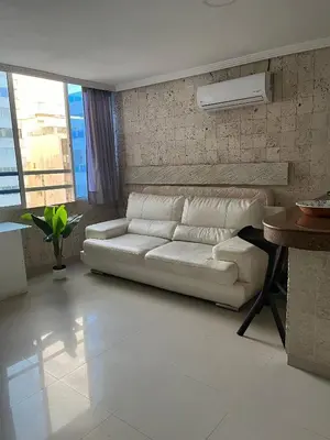 a living room with a white couch and a table at Lindo Apartstudio en El Laguito in Cartagena de Indias