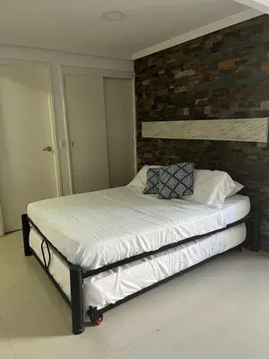 a bed in a bedroom with a brick wall at Lindo Apartstudio en El Laguito in Cartagena de Indias