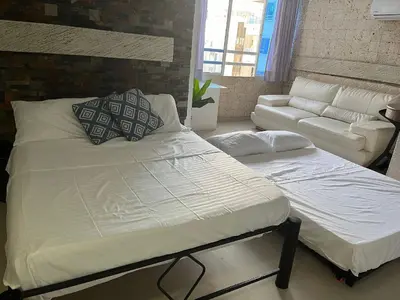 a bedroom with a large bed and a couch at Lindo Apartstudio en El Laguito in Cartagena de Indias