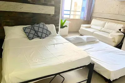 a bed and a couch in a living room at Lindo Apartstudio en El Laguito in Cartagena de Indias
