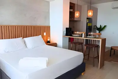 a bedroom with a white bed and a kitchen at Lujoso Apart Studio frente al Mar in Cartagena de Indias
