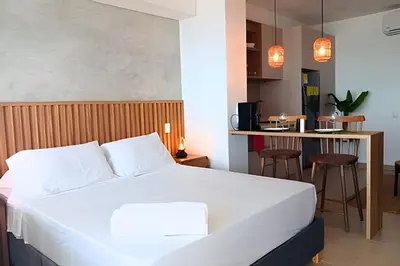 a bedroom with a white bed and a kitchen at Lujoso Apart Studio frente al Mar in Cartagena de Indias