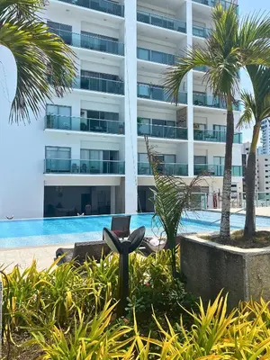 a swimming pool with palm trees and a large building at Chic Apartment Near It All in Cartagena de Indias