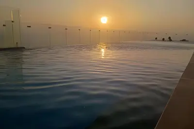a infinity pool with the sun setting in the horizon at Brand New Apt Pool & City Views in Cartagena de Indias