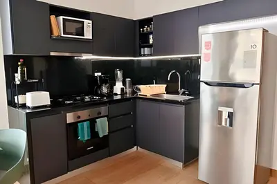 a kitchen with black cabinets and a refrigerator at Brand New, 3blocks from Walled C, Stunning Views in Cartagena de Indias