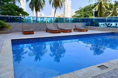 a swimming pool with chaise lounge chairs next to a building at Apto a pasos de la playa, ubicación perfecta in Cartagena de Indias