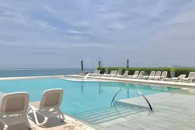 a swimming pool with chairs and the ocean in the background at Breathtaking ocean view, central location in Cartagena de Indias