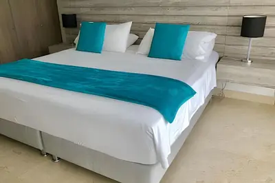 a large bed with blue and white sheets and pillows at Breathtaking ocean view, central location in Cartagena de Indias