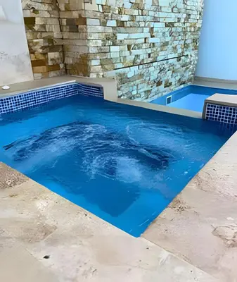 a swimming pool with blue water in front of a stone wall at Charming Loft near the Beach in Cartagena de Indias