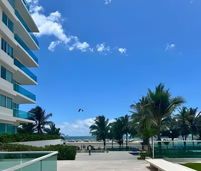 a blue sky with palm trees and a building at Lindo apto con salida directa a la playa in Cartagena de Indias
