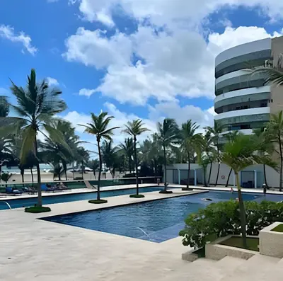 a swimming pool with palm trees and a building at Lindo apto con salida directa a la playa in Cartagena de Indias