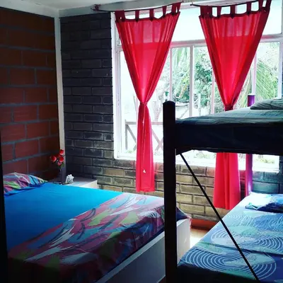 a bedroom with two beds and a window with red curtains at Monkey Afro Hostel in San Antero