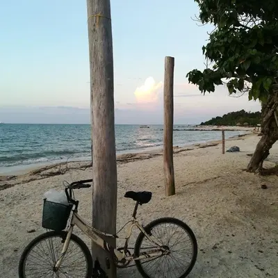 a bike parked next to a pole on the beach at Monkey Afro Hostel in San Antero