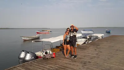 two women standing on a dock with a boat at Monkey Afro Hostel in San Antero