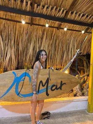 a woman is holding a surfboard in a room at Monkey Afro Hostel in San Antero