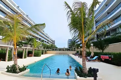 a group of people in a swimming pool with palm trees at Lujoso, último piso con salida directa a la playa in Cartagena de Indias