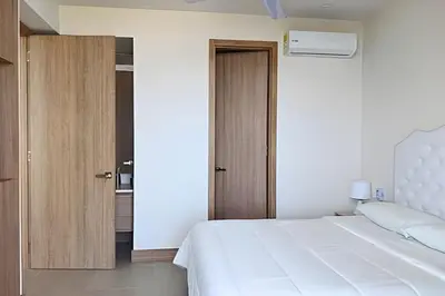 a bedroom with a white bed and a wooden door at Lujoso, último piso con salida directa a la playa in Cartagena de Indias