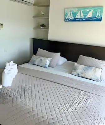 a bed with white sheets and blue pillows on it at Amazing Ocean View, 2B in Bocagrande in Cartagena de Indias