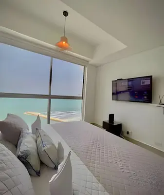 a bedroom with a large white bed with a flat screen tv at Amazing Ocean View, 2B in Bocagrande in Cartagena de Indias