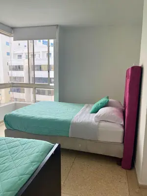 two beds in a room with a window at Bello apartamento con acceso directo a la playa in Cartagena de Indias