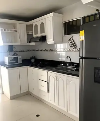 a kitchen with white cabinets and a stainless steel refrigerator at Bello apartamento con acceso directo a la playa in Cartagena de Indias