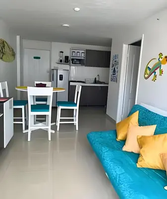a living room with a blue couch and a kitchen at Precioso apto en el Laguito a pasos de la playa in Cartagena de Indias