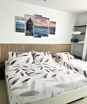two beds in a bedroom with three paintings on the wall at Precioso apto en el Laguito a pasos de la playa in Cartagena de Indias