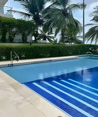 a blue swimming pool with palm trees in the background at Beachfront Paradise with Pools and Spa in Cartagena de Indias