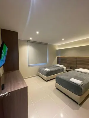 two beds in a room with a tv and a screen at Apto Grand- Ithiel in Barranquilla