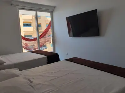 a bedroom with two beds and a flat screen tv on the wall at Apartamento en la Boquilla, Cartagena in Cartagena de Indias
