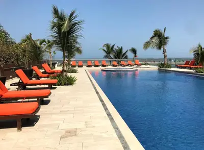 a swimming pool with orange lounge chairs and the ocean at View, exit to Playa Morros tres Cartagena in Cartagena de Indias
