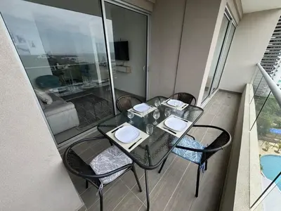 a balcony with a glass table and chairs in a room at Apto Lujo Vista Mar Piscina AC WIFI Playa a 3 min en Santa Marina in Santa Marta