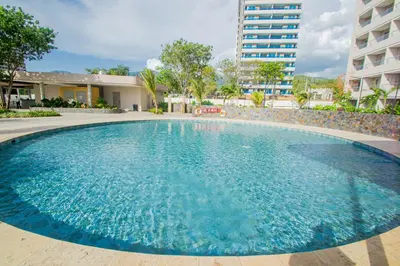 a large pool with blue water in front of a building at Apto Lujo Vista Mar Piscina AC WIFI Playa a 3 min en Santa Marina in Santa Marta