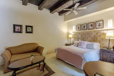 a bedroom with a bed and a couch and a table at Estrella de San Pedro B&B in Cartagena de Indias
