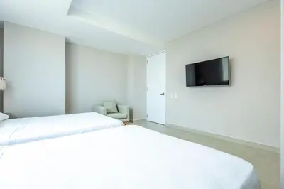 a white room with two beds and a television at Luxurious Beachfront 3BR, Pool & Ocean Views in Cartagena de Indias