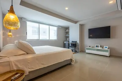 a bedroom with a bed and a flat screen tv at Luxurious Beachfront 3BR, Pool & Ocean Views in Cartagena de Indias