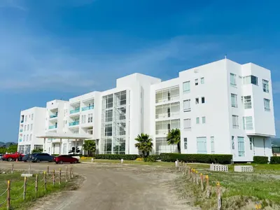 a white building with cars parked in front of it at Cabaña frente al mar in Tubará