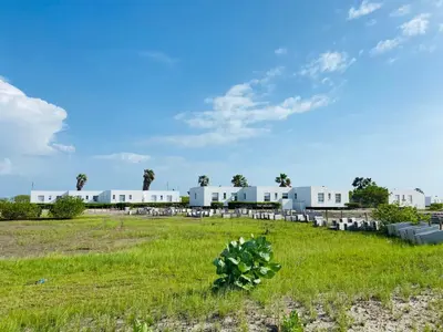 a field with white buildings in the background at Cabaña frente al mar in Tubará