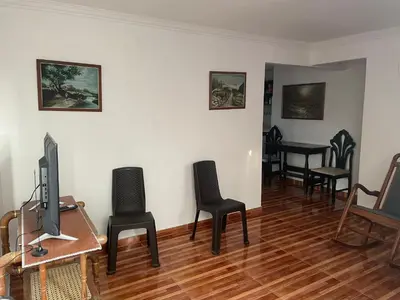 a living room with chairs and a table with a television at Posada Encanto Cartagena in Cartagena de Indias