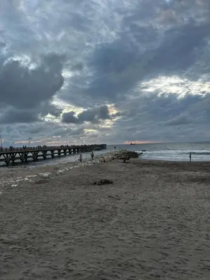 a sandy beach with a pier and the ocean at La Rosita in Puerto Colombia