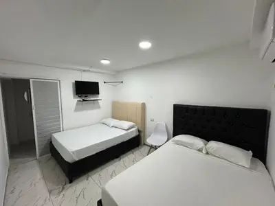 a bedroom with two beds and a tv on the wall at Lago Hotel Cartagena in Estación El Salto