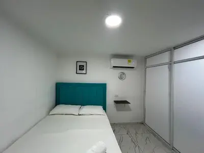 a small bedroom with a bed and a blue headboard at Lago Hotel Cartagena in Estación El Salto