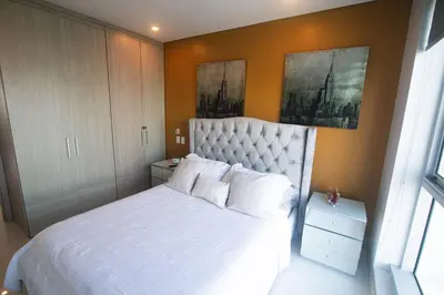 a bedroom with a large bed with white sheets and pillows at Oceanview Suite with two Pools, Gym & Guest Access in Cartagena de Indias