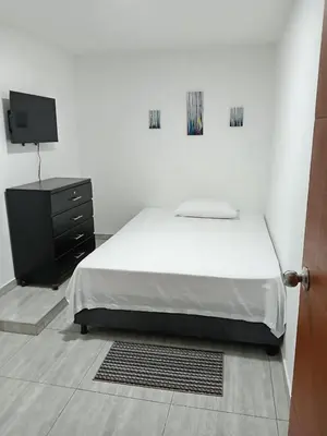 a bedroom with a bed with a dresser and a tv at Casa 19 in Ciénaga