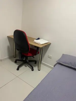 a desk with a red chair next to a bed at Apartamento Alameda del Rio in Barranquilla