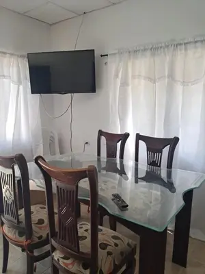 a dining room table with four chairs and a television at Hospedaje Mango y Mar Apartamento in Coveñas