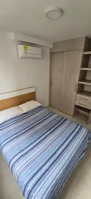 a bedroom with a bed with a blue striped blanket at Apartamento Plazuela Portal Del Prado in Barranquilla