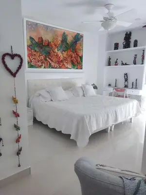 a white bedroom with a bed and a painting on the wall at Apartamento con excelente Vista al Mar in Cartagena de Indias