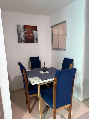 a dining room table with blue chairs and a painting at Apartamento moderno en norte de la ciudad in Barranquilla